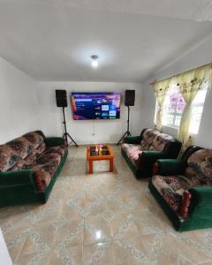 a living room with couches and a flat screen tv at Alojamiento Casa Chuy in Jicolapa