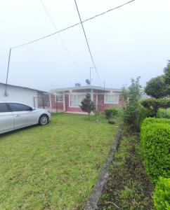 a house with a car parked in the yard at Alojamiento Casa Chuy in Jicolapa