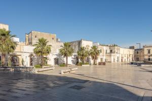 a courtyard with palm trees in front of a building at Celine Dimora e Suite in Copertino