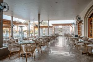 a dining room with tables and chairs and windows at Sentido Akassia Beach Resort in Quseir