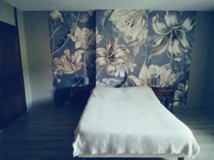 a bedroom with a bed with a floral wallpaper at Les Coquillages in Essoyes