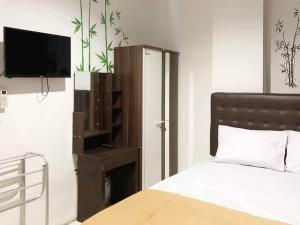 a bedroom with a bed and a tv on the wall at SAS Guest House Mitra RedDoorz At Darmo Park 2 Surabaya in Surabaya