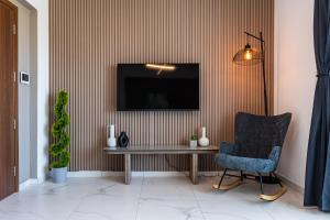 a living room with a table and a chair and a television at Mayan 2-Bedroom Apartment in Larnaca