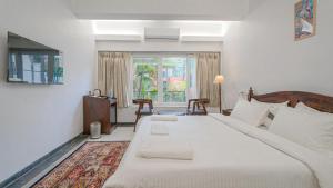 a bedroom with a large white bed and a window at Table Land Retreat in Panchgani