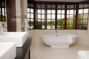 a bathroom with two sinks and a tub and windows at Rawdons Hotel & Brewery in Nottingham Road