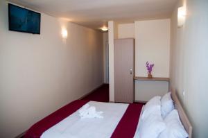 um quarto com uma cama com lençóis brancos e uma televisão na parede em Dumbrava Minunata em Brasov
