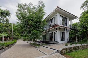 a white house with a walkway in front of it at RedDoorz at Batutulis Bogor Villa Papatong by M in Bogor
