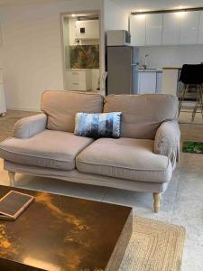 a couch in a living room with a kitchen at Maison privée spacieuse avec piscine chauffée pour 8 personnes in Joué-lès-Tours