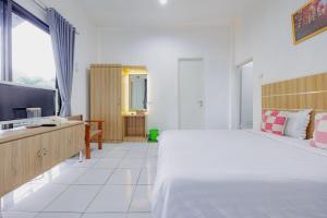 a bedroom with a large bed and a television at RedDoorz at Batutulis Bogor Villa Papatong by M in Bogor