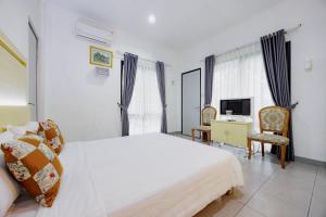 a bedroom with a bed and a desk and a television at RedDoorz at Batutulis Bogor Villa Papatong by M in Bogor