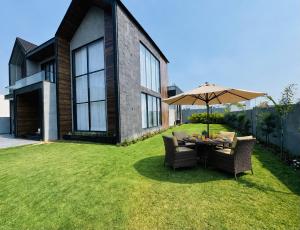 a table with an umbrella and chairs on a lawn at Sukoon Luxury Stay in Amritsar