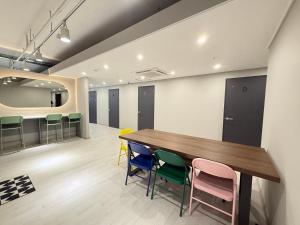 a conference room with a wooden table and colorful chairs at Hostel K wave Only Female Hongdae in Seoul