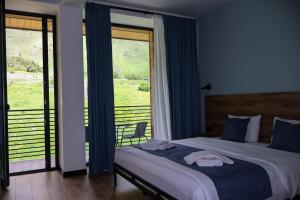 a bedroom with a bed and a large window at Kazbegi Hotel Grand View in Kazbegi