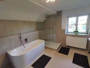 eine weiße Badewanne in einem Badezimmer mit Fenster in der Unterkunft Grey House in Laufen