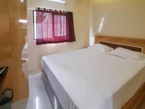 a white bed in a room with a red window at Jatiwangi Syariah Guest House Mitra RedDoorz in Majalengka