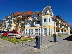 a large yellow building with a red car parked in a parking lot at Fiore Wellness Apartman in Zalakaros +52 photos