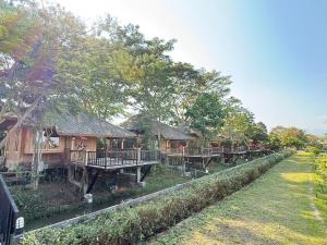 a row of cottages with tables and trees at เพลินนะเพลินนา รีสอร์ต Ploennaploenna in Ban Rim Lao