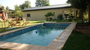 a swimming pool in a yard with chairs and a house at Cabañas Don Roque in Chilecito