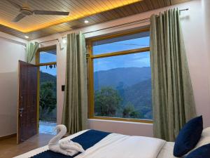a bedroom with a large window with a swan on the bed at Pahadi Aangan Chakrata in Kailāna