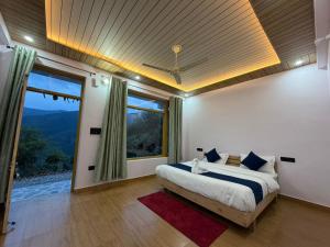 a bedroom with a bed and a large window at Pahadi Aangan Chakrata in Kailāna