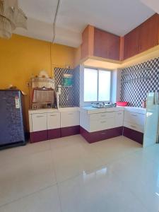 a large kitchen with white cabinets and a window at Siddhi Home Stay in Kolhapur