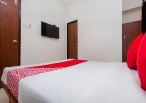 a bedroom with a white bed with red pillows at Hotel Cliff Hanger in Mumbai