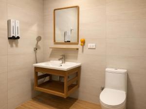 a bathroom with a toilet and a sink and a mirror at Songfeng B&B in Luye