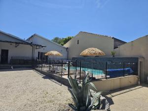 a fence with umbrellas next to a swimming pool at Loft entre vignes et truffes - Gite en Provence Vaucluse in Valréas