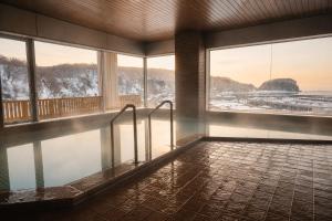a swimming pool in a building with snow on the ground at Rembrandt Resort Shiretoko in Shari