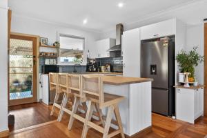 a kitchen with a counter with chairs and a refrigerator at Styled Entertainer only mins from CBD in Bendigo