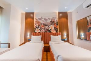 two beds in a room with a painting on the wall at Royal Ritis in Shimoga +51 photos