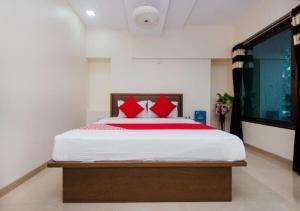 a bedroom with a large bed with red pillows at Hotel Cliff Hanger in Mumbai