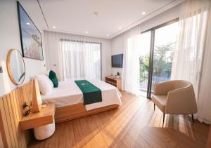 a large bedroom with a bed and a chair in it at Villa The Pearl -Vlasta Sầm Sơn in Sầm Sơn