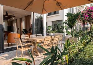 a wooden table and chairs with an umbrella on a patio at Villa The Pearl -Vlasta Sầm Sơn in Sầm Sơn