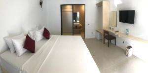 a bedroom with a large white bed and a desk at Zukara Maldives in Thoddoo