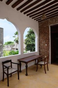 a table and chairs in a room with two windows at Amu House in Lamu