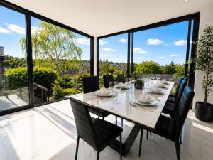 a dining room with a table and chairs and large windows at Luxurious & Elegant 6-Bed House in Barnet