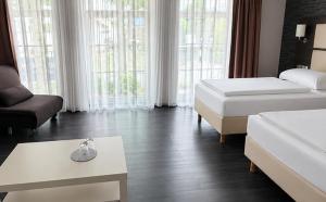 a hotel room with two beds and a couch at DORMERO Hotel Werther in Werther