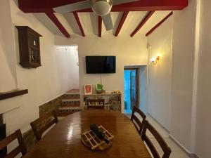 a dining room with a wooden table and a tv at Casa De Pueblo Raval in Teulada