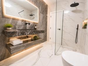 a bathroom with a glass shower and a toilet at Luxurious & Elegant 6-Bed House in Barnet +22 photos
