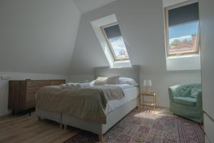 a bedroom with a bed and a chair and two windows at Monbuhim Four in Veszprém