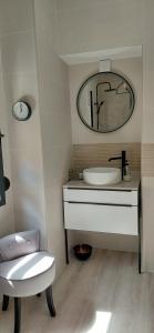 a bathroom with a sink and a mirror and a chair at Lodge au vent in Savigné-lʼÉvêque