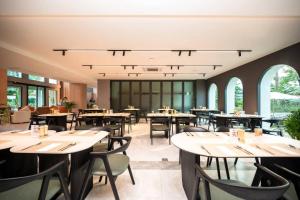 ein Restaurant mit Tischen, Stühlen und Fenstern in der Unterkunft The Clover in Chiang Mai