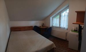 a small bedroom with a bed and a window at Cyklami in Pobierowo