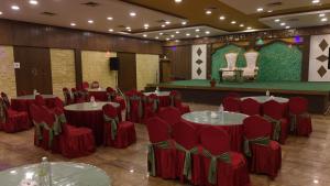 a banquet hall with red chairs and tables and a stage at Bardibas Resort in Tulsi