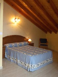 1 dormitorio con 1 cama en una habitación con techos de madera en Casa Rural Maribel II, en Cue