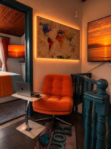 an orange chair in a bedroom with a desk and a laptop at Melis House - Lake View, 75'' TV Live Football, Free Parking in Ioannina
