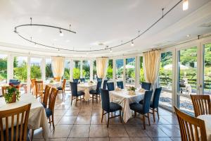 a dining room with tables and chairs and windows at Hotel Hanny Panoramic Views over Bolzano in Bolzano