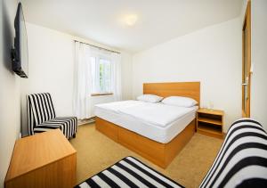 ein kleines Schlafzimmer mit einem Bett und einem Stuhl in der Unterkunft Element Residence in Lipno nad Vltavou