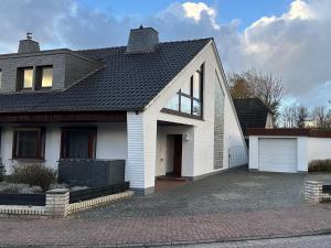 a white house with a black roof and a driveway at Strandloft Pippa in Borkum
